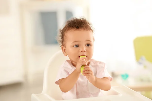 Schattige baby met lepel zit in kamer — Stockfoto