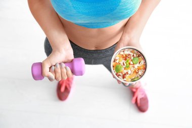 Genç kadın dumbbell ve yulaf ezmesi ile kase elinde tutan