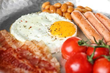 Tavada yumurta, fasulye, sosis, pastırma ve kiraz domates ile