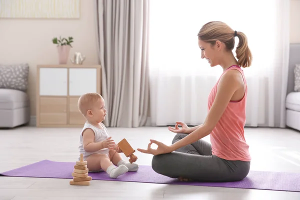 Jovem mãe fazendo ioga com bebê em casa — Fotografia de Stock