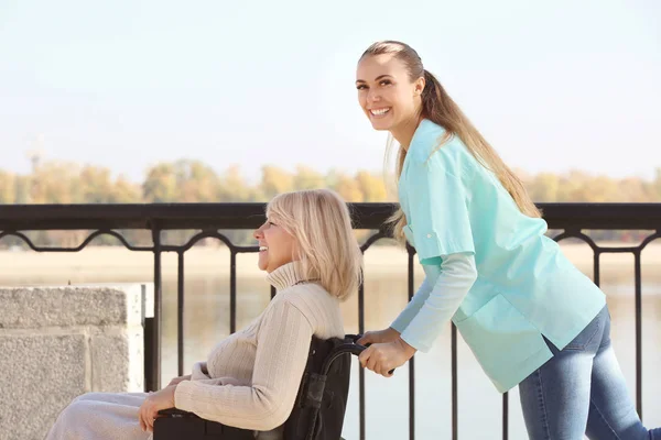 Handikappad äldre kvinna och ung vårdare — Stockfoto