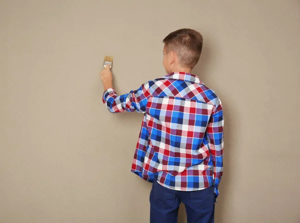 Söt liten pojke målning vägg med borste — Stockfoto