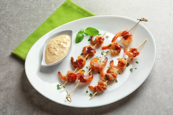 Plate med skråreker pakket inn i bacon og saus – stockfoto