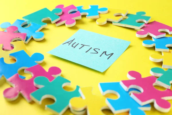Zusammensetzung verschiedener Rätsel und Aufkleber mit Wort Autismus auf farbigem Hintergrund — Stockfoto