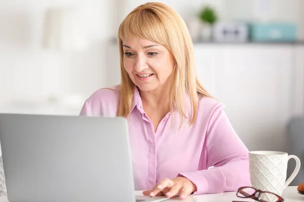 Mulher madura bonita trabalhando no laptop em casa — Fotografia de Stock