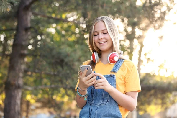 Retrato de linda adolescente con auriculares y teléfono móvil al aire libre —  Fotos de Stock
