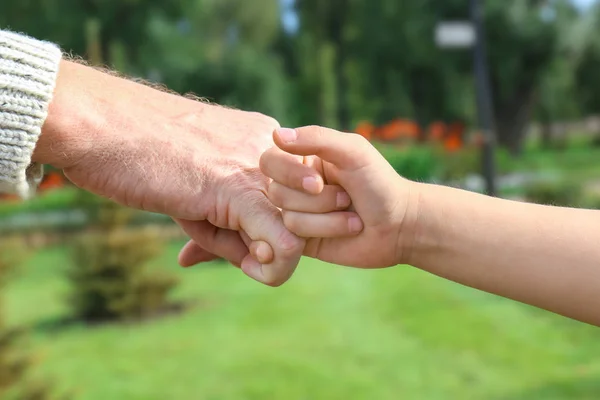 Äldre man och hans barnbarn att göra pinky löfte på suddig bakgrund — Stockfoto