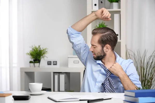 Young man sweating in office