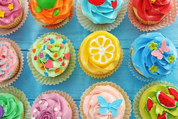 Beautiful cupcakes on color wooden backgroun — Stock Photo, Image