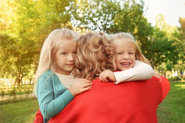 Cute little girls hugging grandmother in park — Stock Photo, Image