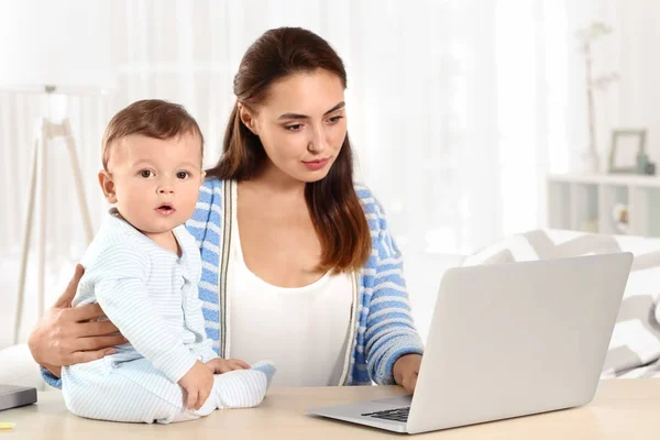 Giovane madre che tiene in braccio il bambino mentre lavora in ufficio — Foto Stock