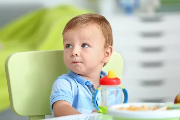 Bebê adorável sentado à mesa dentro de casa — Fotografia de Stock