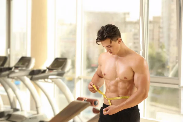 Muskulös ung man med måttband i gym — Stockfoto