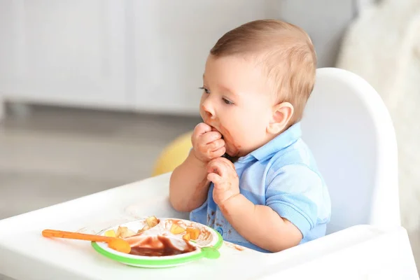 Söt rörig baby äter puré hemma — Stockfoto