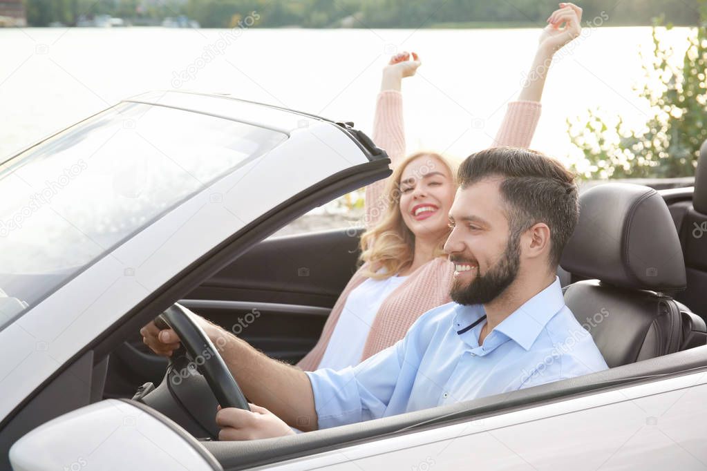 Happy young couple in car on road trip