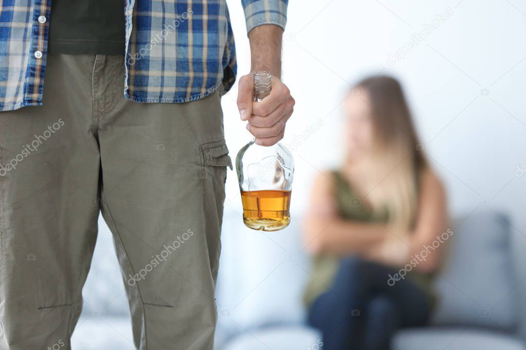 Man with bottle of alcohol and blurred woman