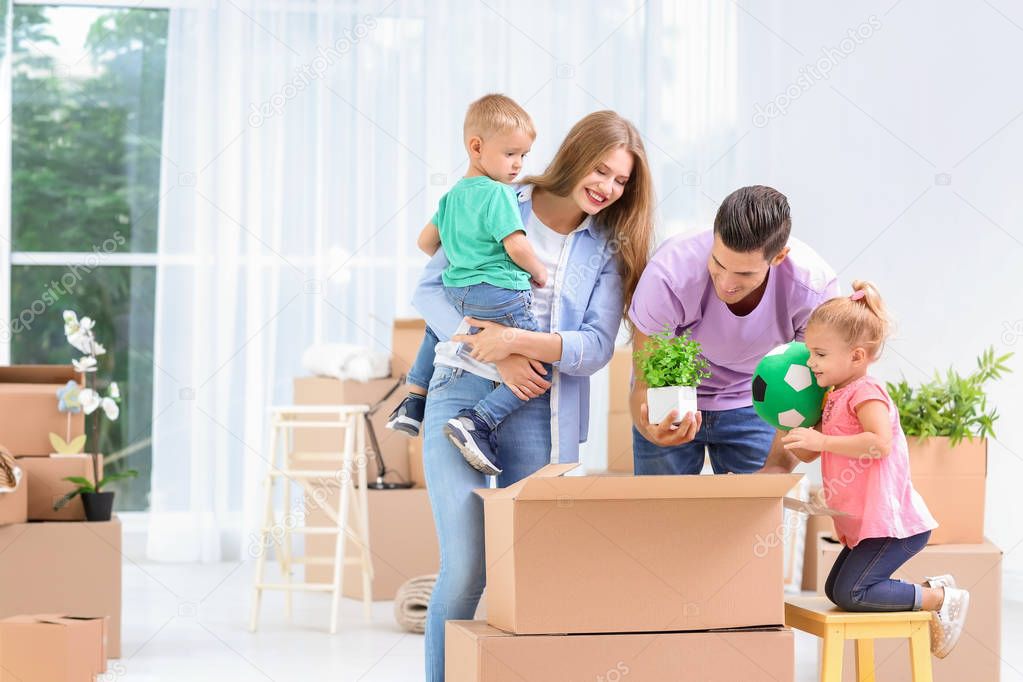 Happy family unpacking moving boxes in their new house