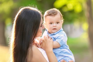 Güzel genç anne holding şirin bebek çocuk, açık havada