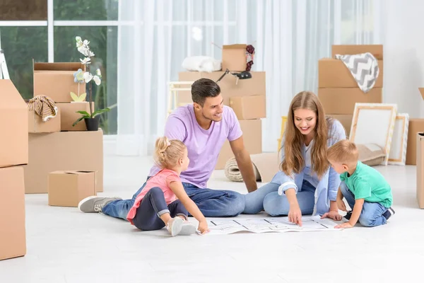 Familie studiert Plan ihres neuen Hauses, während sie auf dem Fußboden sitzt — Stockfoto