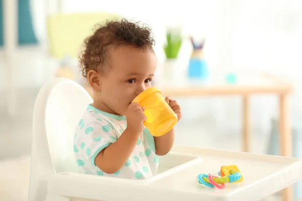 Schattige baby drinkwater binnenshuis — Stockfoto