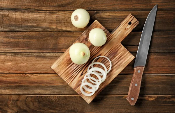 Planche à découper avec oignon frais et couteau — Photo