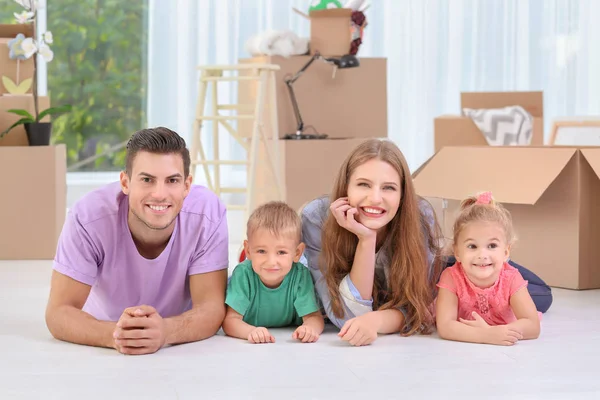 Glückliche Familie liegt auf dem Boden in der Nähe von Umzugskartons in ihrem neuen Haus — Stockfoto