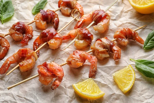 Skewered shrimps wrapped in bacon on parchment — Stock Photo, Image