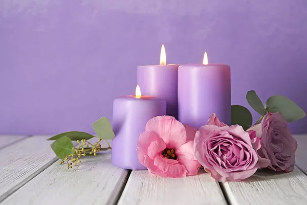 Velas ardientes púrpura con flores — Foto de Stock