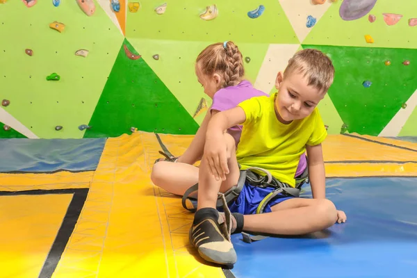 Adorable little children putting on shoes in climbing gym — Stock Photo, Image