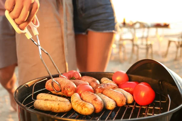 Mand madlavning pølser og grøntsager på grill grill - Stock-foto
