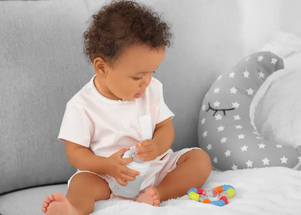 Lindo bebé con biberón de agua en el sofá en casa — Foto de Stock