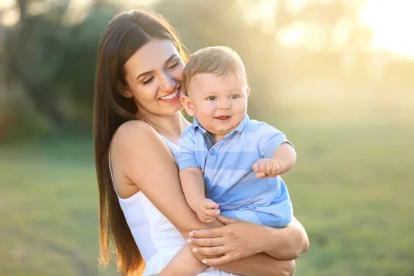Vacker ung mamma innehav söt baby pojke, Utomhus — Stockfoto