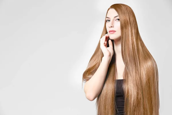 Jeune femme avec de beaux cheveux longs de couleur caramel sur fond clair — Photo