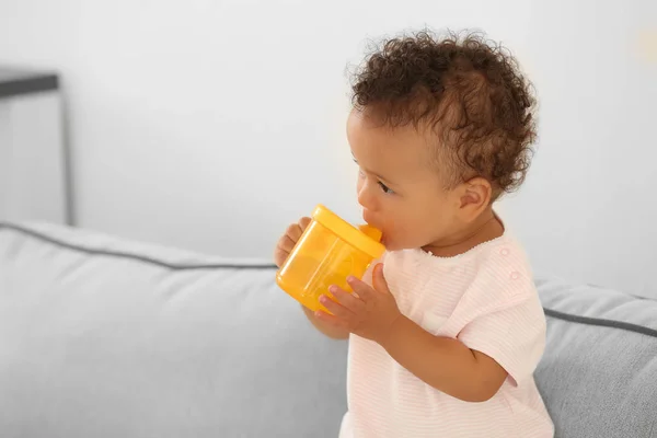 Schattige baby met flesje water op de sofa thuis — Stockfoto