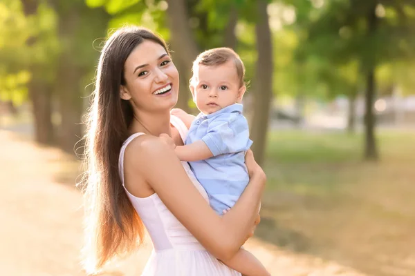 Beautiful young mother holding cute baby boy, outdoors — Stock Photo, Image