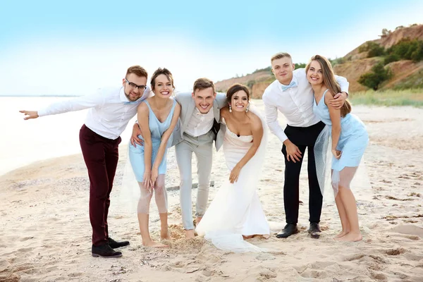 快乐的新婚夫妇和海滩上的朋友玩得开心 — 图库照片