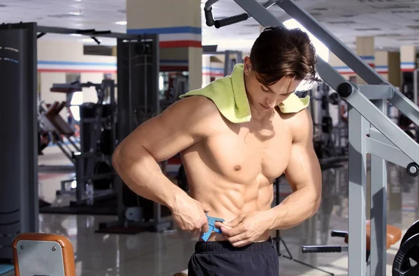 Musculoso joven utilizando la pinza de grasa corporal en el gimnasio —  Fotos de Stock