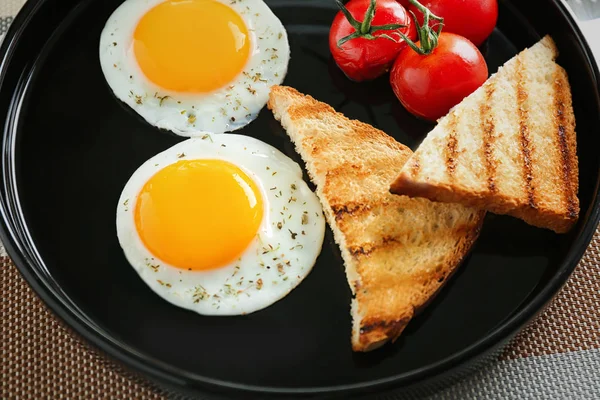 Тарелка с жареными яйцами, тостами и помидорами черри — стоковое фото