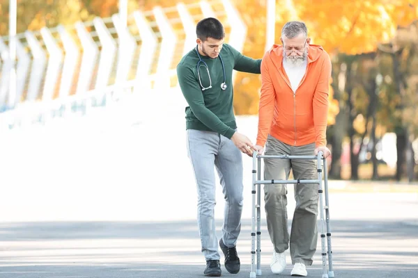 Caregiver a piedi con l'uomo anziano — Foto Stock