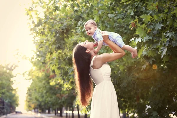 Ibu muda yang cantik menggendong bayi laki-laki lucu, di luar ruangan — Stok Foto