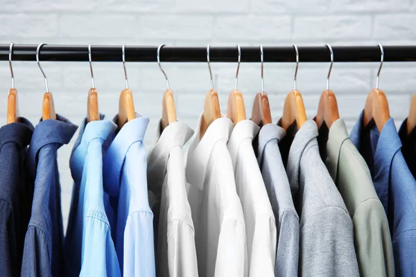 Jackets and shirts hanging on clothing rail — Stock Photo, Image