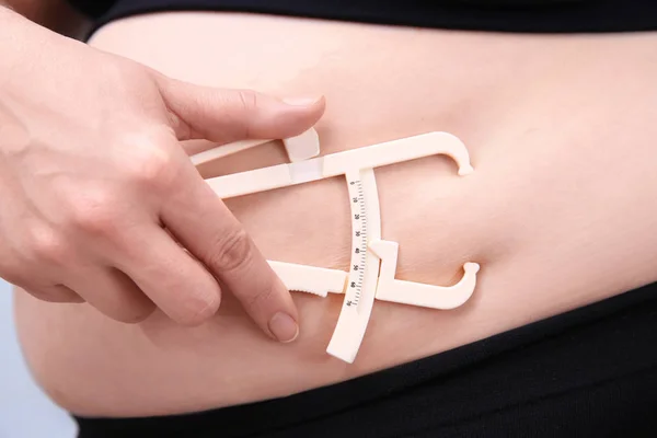 Mujer con sobrepeso con pinza de medición — Foto de Stock