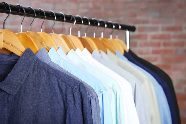 Jaquetas e camisas penduradas no trilho de roupas — Fotografia de Stock