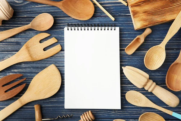 Notebook and various kitchen utensils on wooden background — Stock Photo, Image