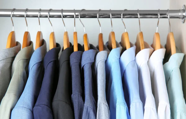 Jaquetas e camisas penduradas no trilho de roupas — Fotografia de Stock