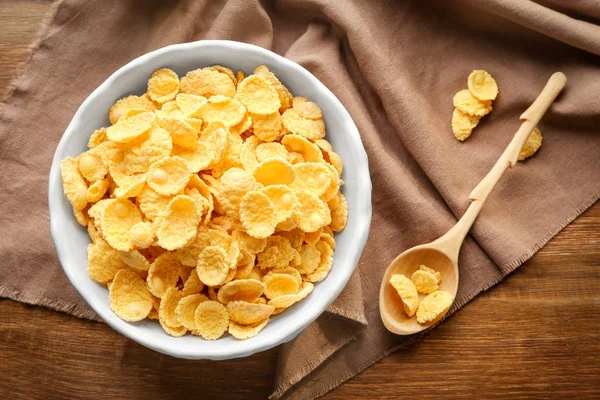 Skål och sked med välsmakande majsflingor på bord — Stockfoto