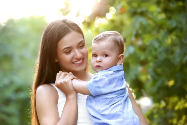 Bello giovane madre holding carino bambino ragazzo, all'aperto — Foto Stock