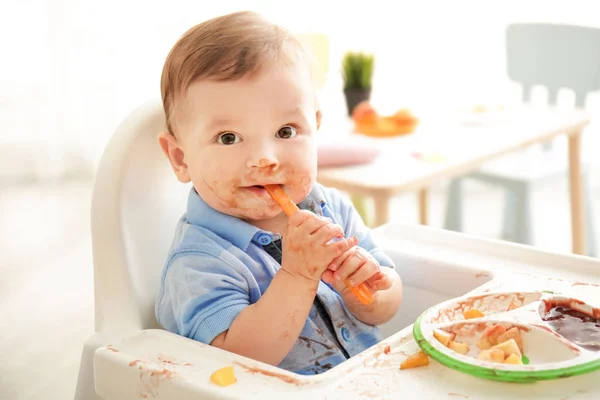 Söt rörig baby äter puré hemma — Stockfoto