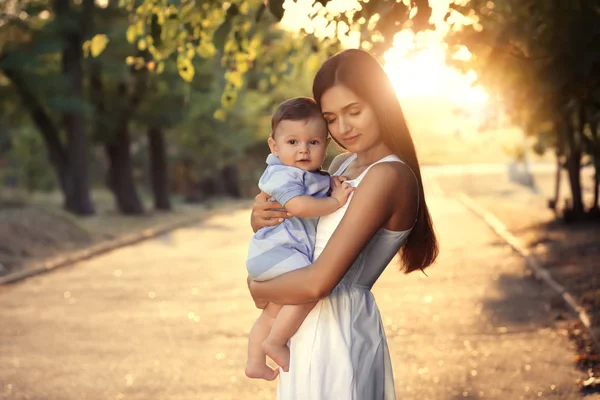 Bello giovane madre holding carino bambino ragazzo, all'aperto — Foto Stock