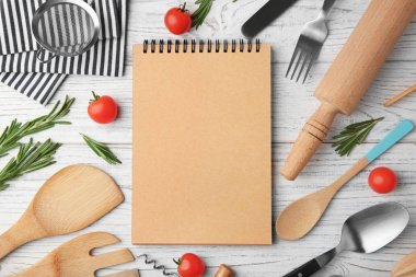 Defter ve ahşap arka plan üzerinde çeşitli mutfak eşyaları